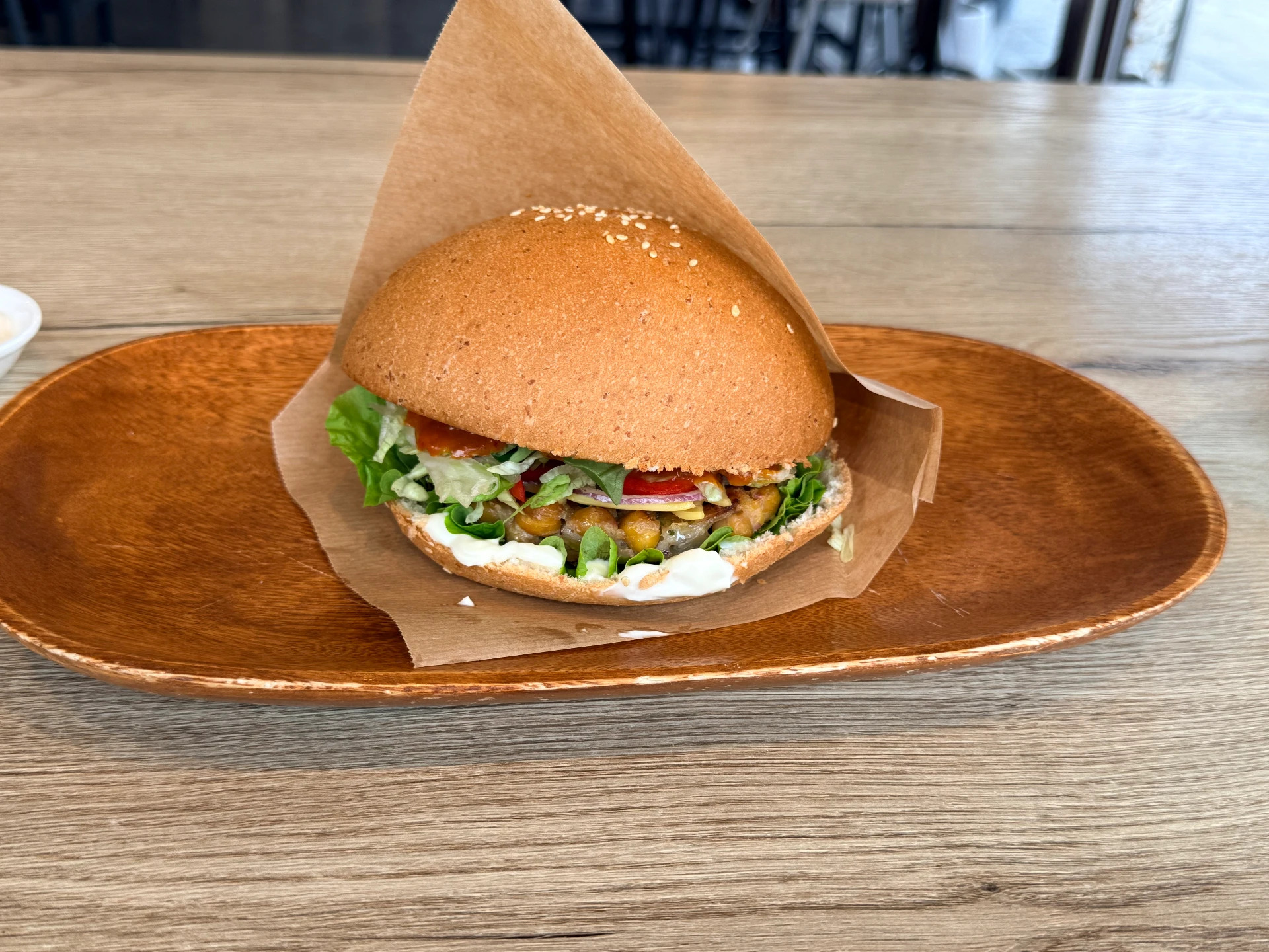 Veganer Burger im Einschlagpapier auf einem Holzteller