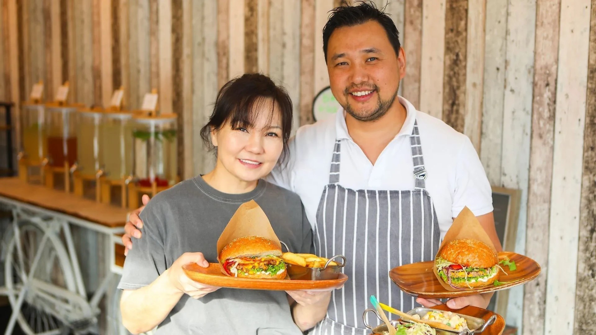 Das Team von Mongol Burger mit zwei veganen Burgern auf Holztellern